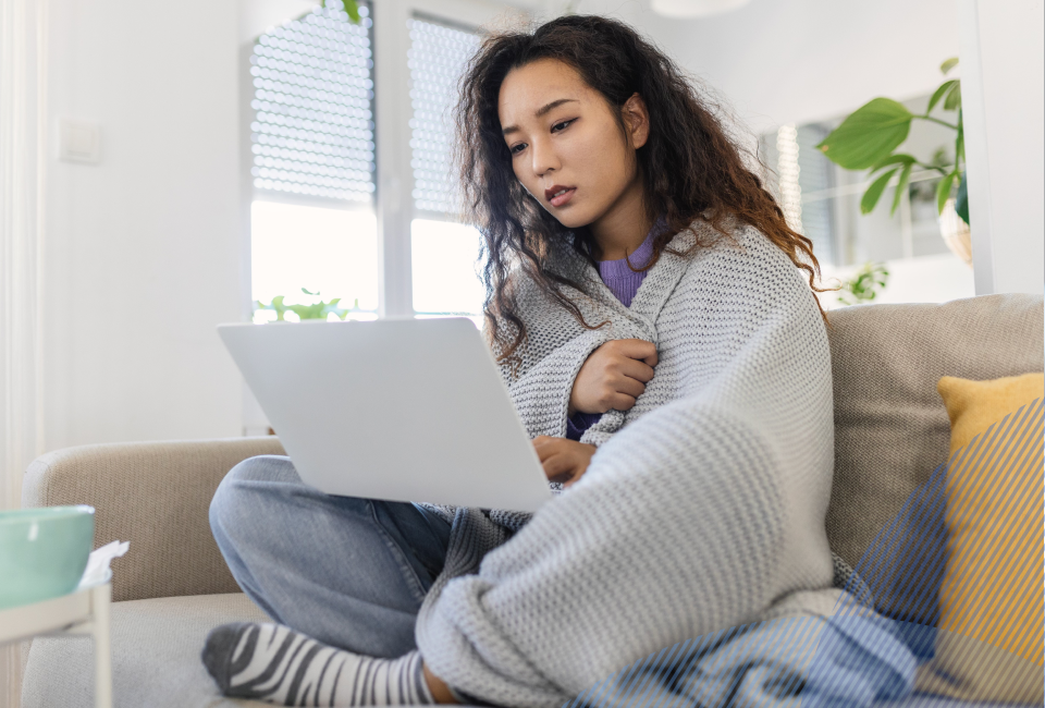 woman wrapped in a blanket, sitting with her laptop